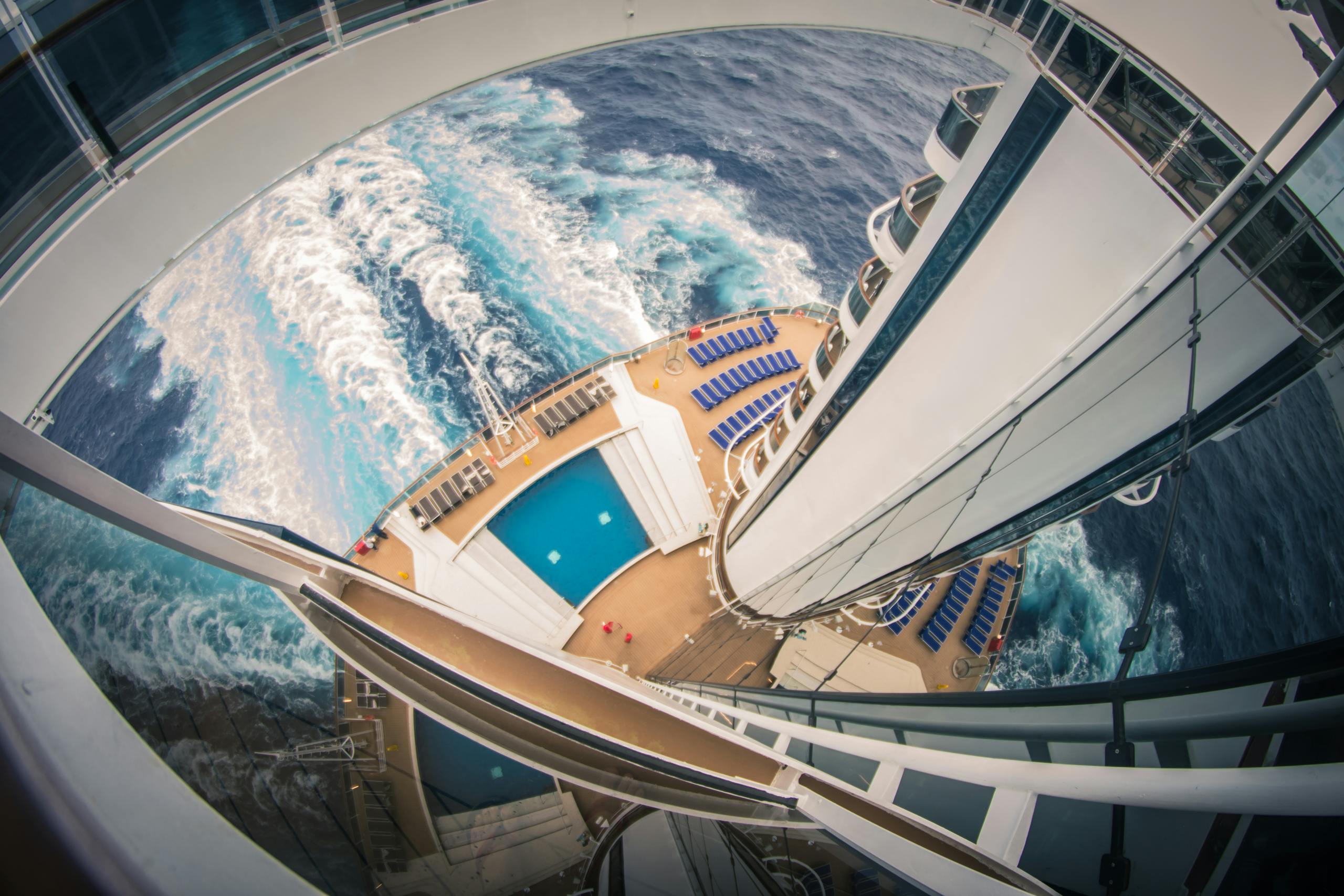 High angle view of a luxury cruise ship at sea, showcasing the pool deck and ocean waves.